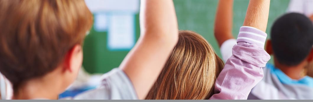 Back view of kids raising hands in a classroom. ©Joshua Hodge Photography/the Agency Collection/Getty Images